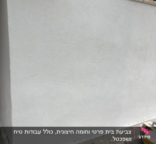 קיר צבוע בלבן עם דלי צבע וכלי עבודה